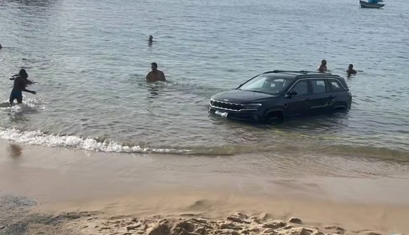 Imagem de Motorista estaciona carro na praia do Porto da Barra e veículo é parcialmente submerso após maré subir